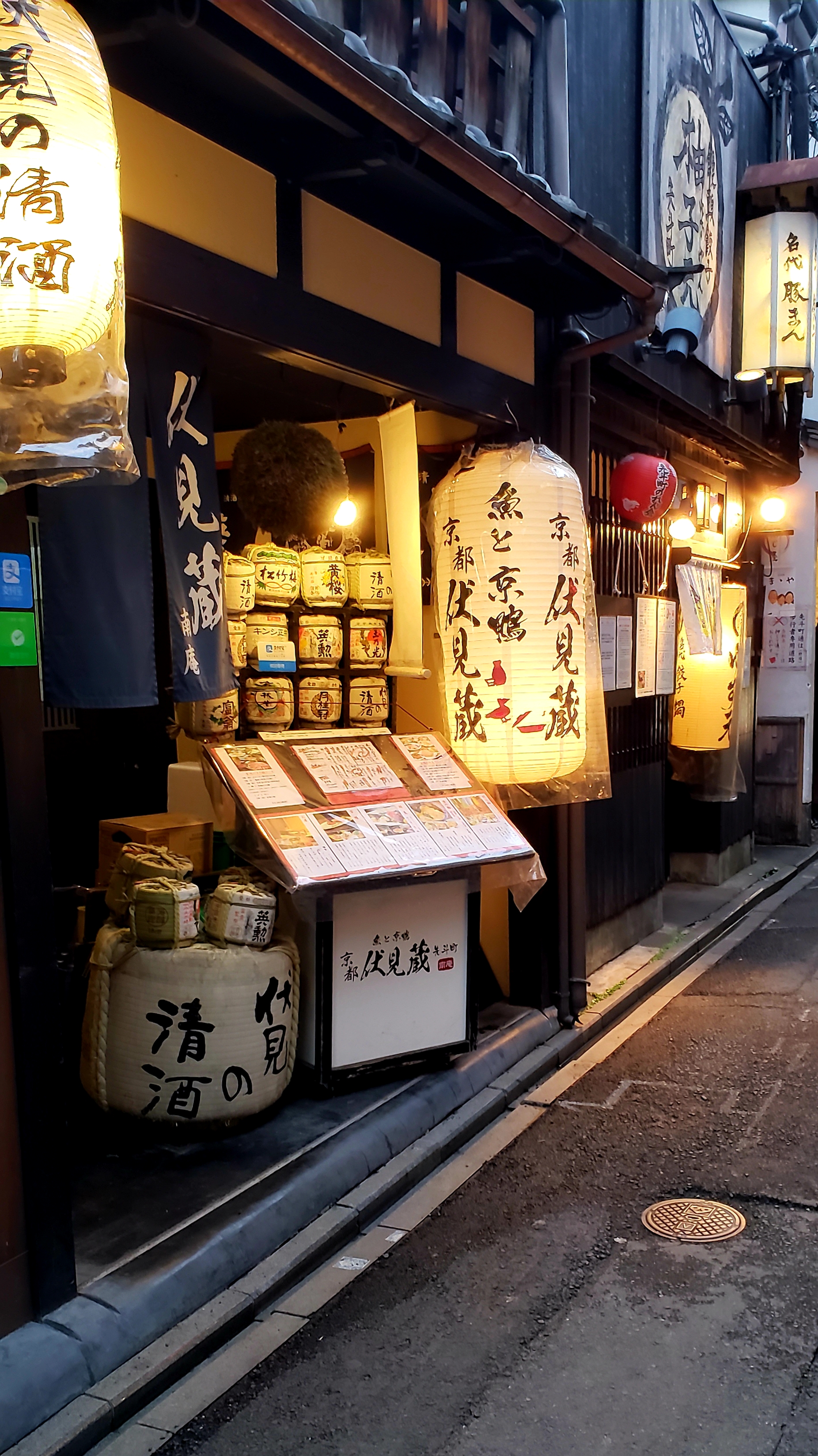 Lanterns, sake barrels and menu in front of Japanese restaurant at dusk