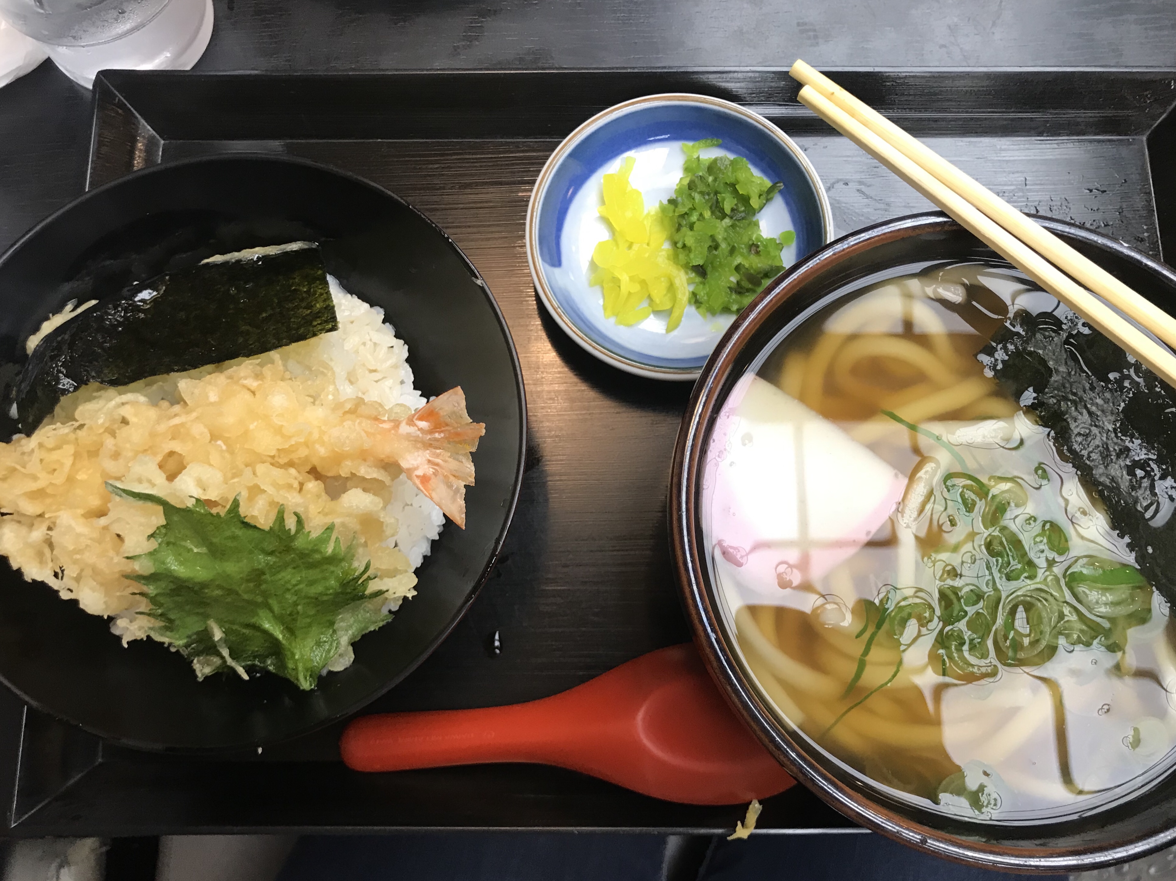 Bowl of noodles and bowl of tempura sitting on tray with chopsticks and red spoon